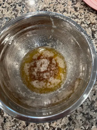 Browned butter in a glass bowl, amber colored with toasted foam on top