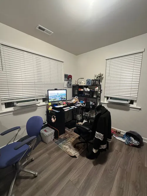 The home office before any changes — harsh overhead light, cluttered L-shaped desk, nothing inviting about it